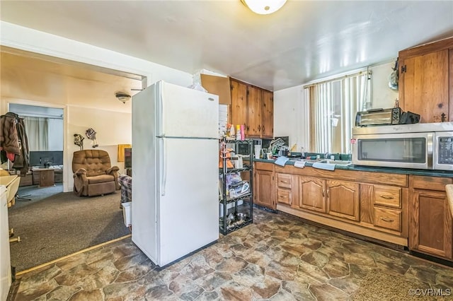 4591 Allen Rd, Jarratt, VA 23867 - kitchen featuring stone finish floor, freestanding refrigerator, stainless steel microwave, and brown cabinets