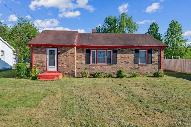 view of front of house with fence, a front yard, a chimney, brick siding, and a shingled roof