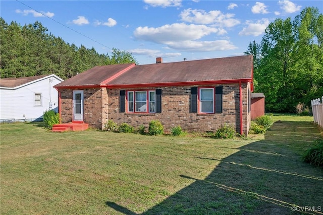 ranch-style house featuring brick siding, a chimney, and a front yard