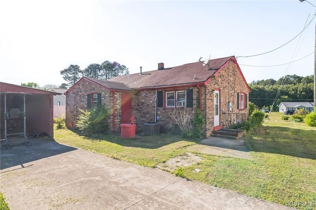 view of front facade with brick siding, a chimney, and a front yard