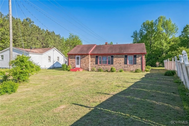 view of front facade featuring fence, a front yard, and brick siding