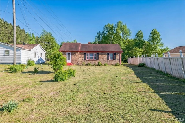 single story home with fence, a chimney, a front lawn, and brick siding