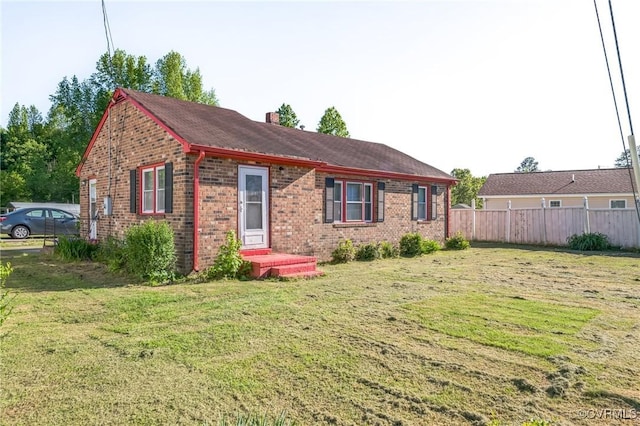 view of front of house with brick siding, fence, a front yard, and a chimney