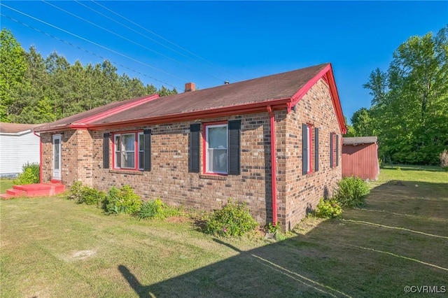 view of side of property featuring a lawn, a chimney, and brick siding