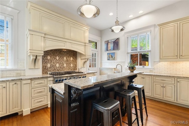 2218 Monument Ave, Richmond, VA 23220 - kitchen featuring cream cabinets, decorative backsplash, stainless steel gas stovetop, recessed lighting, and a breakfast bar
