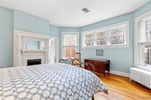 2218 Monument Ave, Richmond, VA 23220 - bedroom featuring radiator, wood finished floors, baseboards, and a brick fireplace