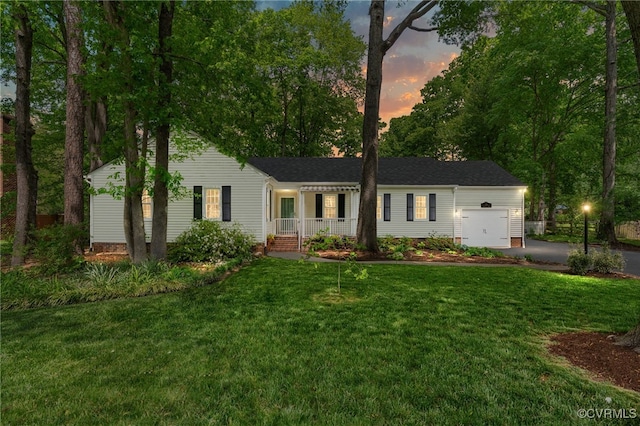 single story home featuring a porch, a garage, aphalt driveway, and a lawn