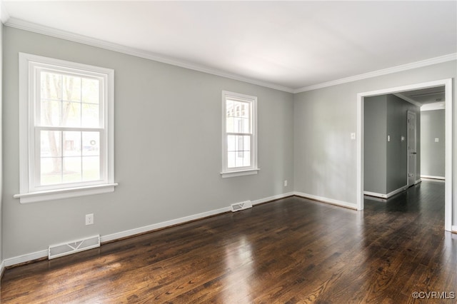 empty room featuring visible vents, dark wood finished floors, crown molding, and baseboards