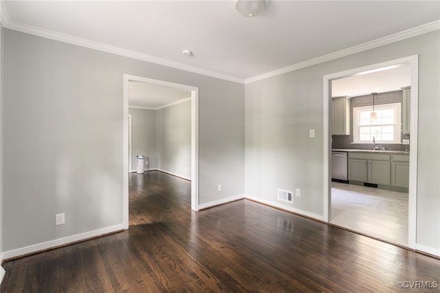 spare room with visible vents, a sink, baseboards, and wood finished floors
