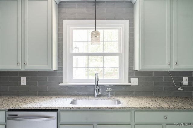 kitchen featuring light stone countertops, a sink, dishwasher, a healthy amount of sunlight, and backsplash