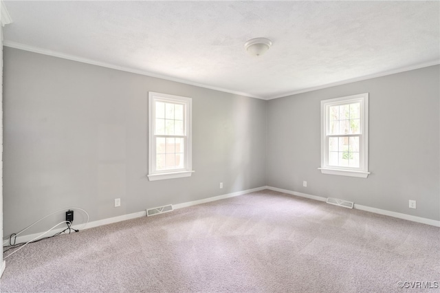 spare room featuring crown molding, baseboards, and visible vents