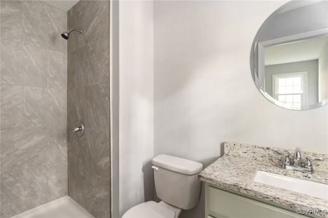 bathroom featuring vanity, toilet, and tiled shower
