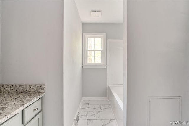 full bath with walk in shower, vanity, marble finish floor, baseboards, and a tub to relax in
