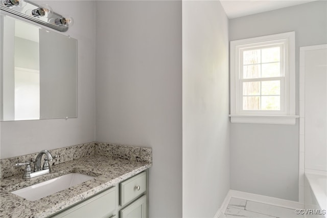 full bath featuring a tub, baseboards, vanity, and marble finish floor