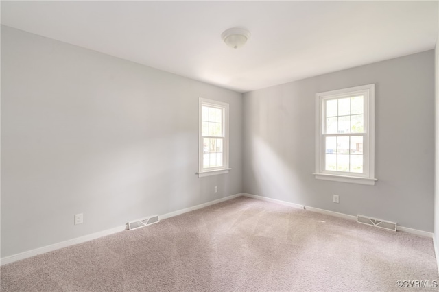 empty room featuring baseboards, visible vents, and a wealth of natural light
