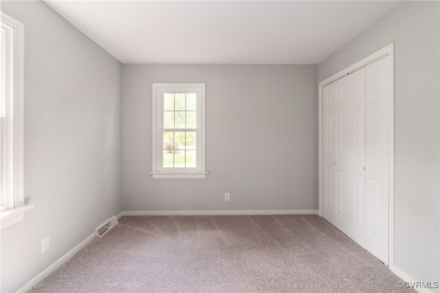 unfurnished bedroom featuring visible vents, carpet, baseboards, and a closet