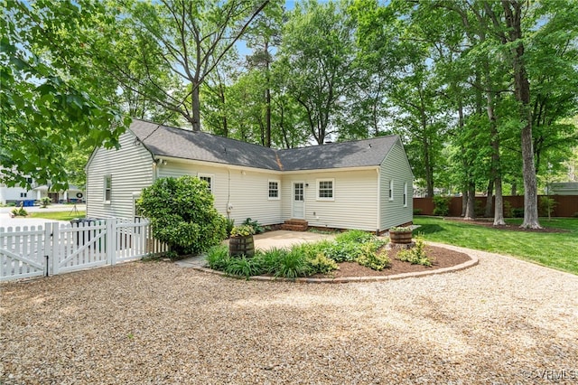rear view of property featuring fence private yard, a patio, roof with shingles, a gate, and a lawn
