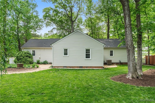 back of property with crawl space, roof with shingles, central air condition unit, fence, and a yard