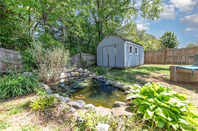10701 Hamiltons Xing, Fredericksburg, VA 22408 - view of yard with an outdoor structure, a fenced backyard, a garden pond, and a storage shed