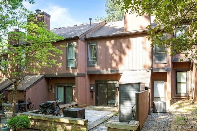 back of property featuring a shingled roof, a chimney, and cooling unit