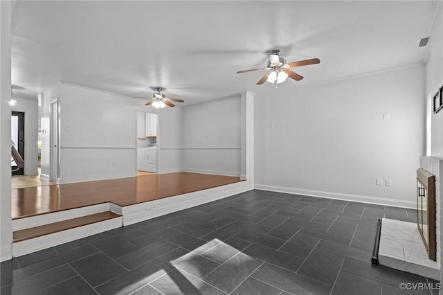 unfurnished living room with a fireplace, a ceiling fan, baseboards, visible vents, and washer and clothes dryer