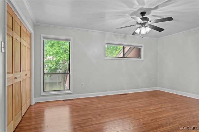 unfurnished room with crown molding, plenty of natural light, and wood finished floors