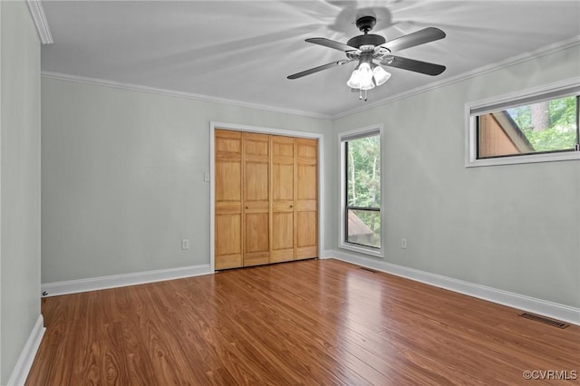unfurnished bedroom featuring visible vents, baseboards, wood finished floors, and a closet
