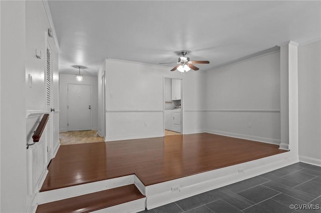 unfurnished living room featuring baseboards, ceiling fan, and washing machine and clothes dryer