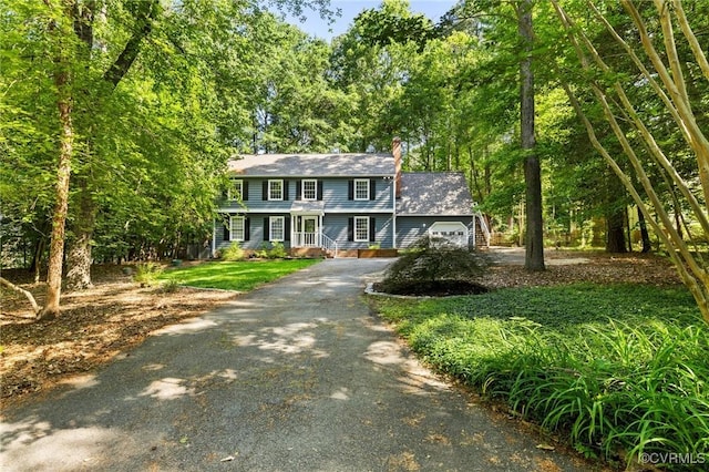 view of front of property featuring driveway, an attached garage, and a chimney