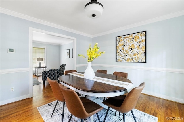 dining area with wood finished floors, baseboards, and crown molding