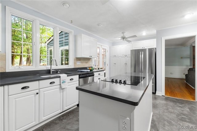 kitchen featuring appliances with stainless steel finishes, a sink, dark countertops, crown molding, and white cabinets