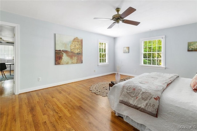 bedroom with multiple windows, wood finished floors, and baseboards