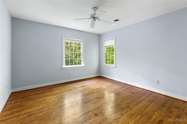 empty room with baseboards, wood finished floors, and a ceiling fan