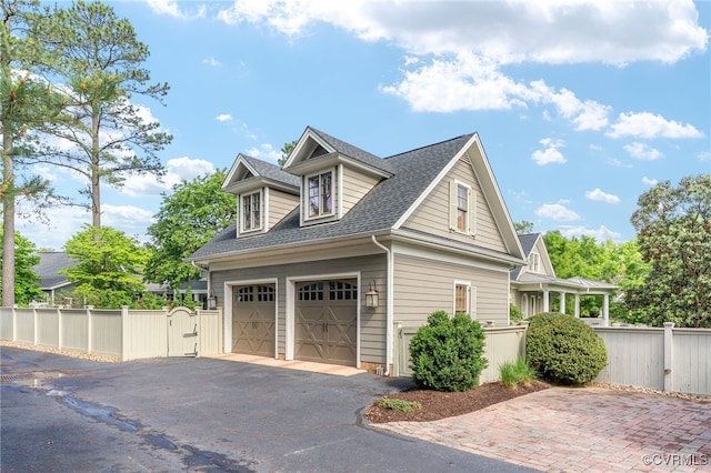 view of property exterior with fence, a gate, and a shingled roof
