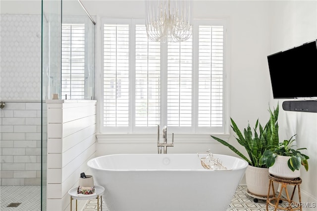 bathroom featuring a chandelier, a freestanding bath, and tiled shower