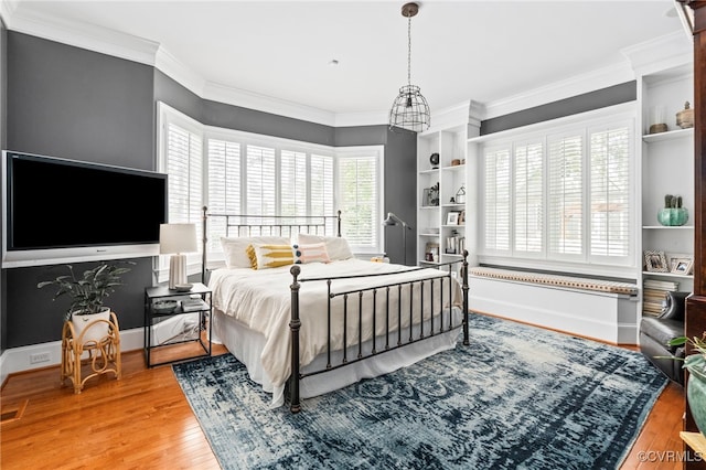 bedroom with wood finished floors, crown molding, and baseboards