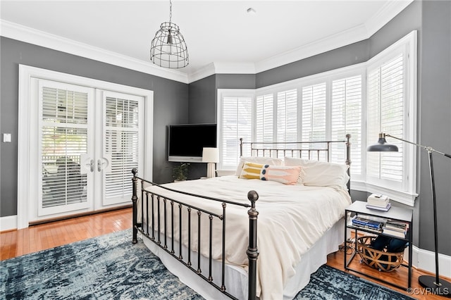 bedroom with access to exterior, wood-type flooring, french doors, ornamental molding, and baseboards
