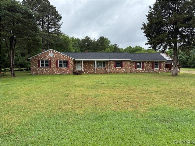single story home featuring brick siding, a chimney, and a front yard