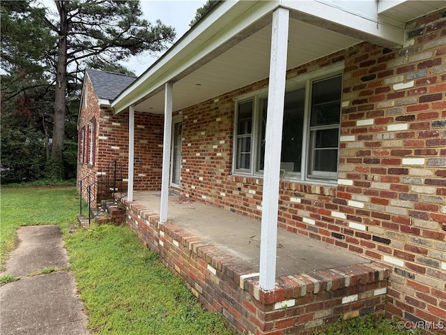 view of property exterior with a porch, brick siding, roof with shingles, and a lawn