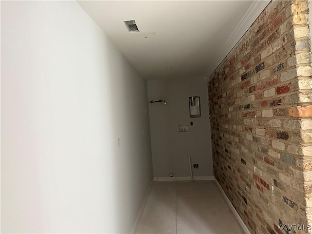 hallway featuring light tile patterned floors, brick wall, and baseboards