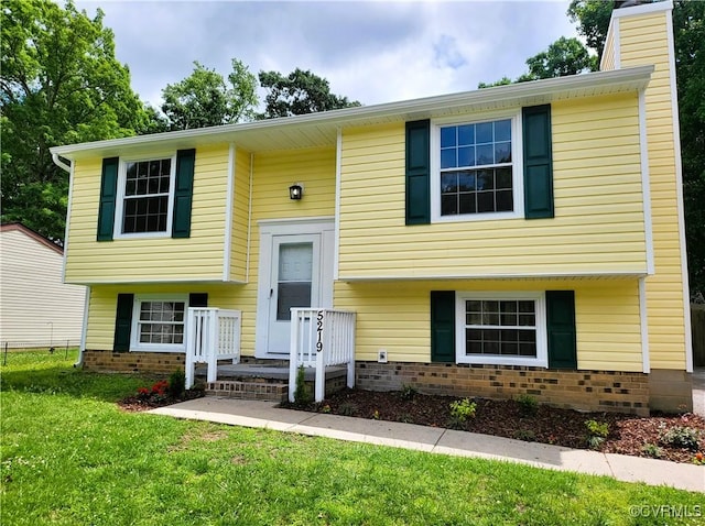 split foyer home with a front lawn, a chimney, and brick siding