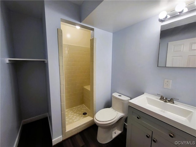 full bathroom with tiled shower, toilet, wood finished floors, and vanity