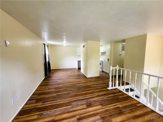 spare room featuring dark wood-type flooring and baseboards