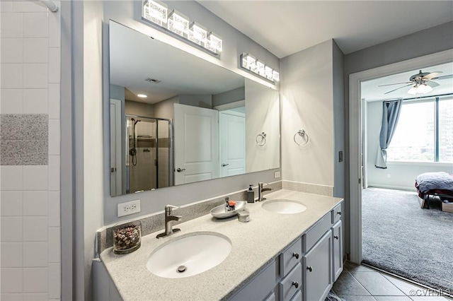 ensuite bathroom with double vanity, a ceiling fan, a shower stall, and a sink
