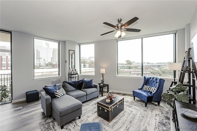 living room featuring baseboards, ceiling fan, and wood finished floors