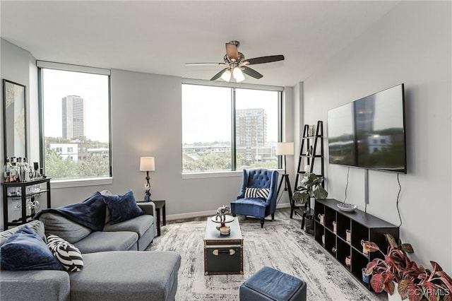 living room featuring baseboards, a ceiling fan, wood finished floors, and a wealth of natural light