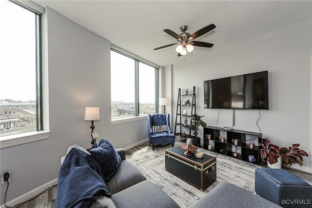 living area featuring baseboards, a ceiling fan, wood finished floors, and a healthy amount of sunlight