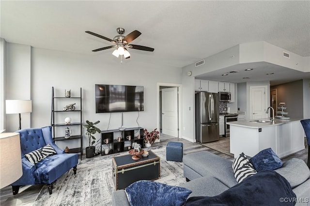 living area featuring visible vents, ceiling fan, and light wood-type flooring