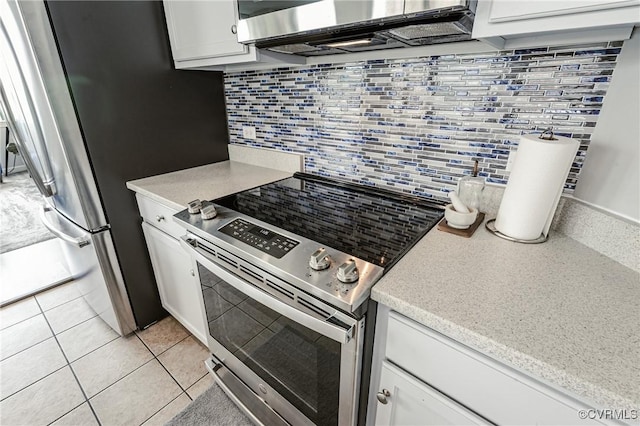 kitchen with light countertops, stainless steel appliances, white cabinetry, light tile patterned floors, and backsplash