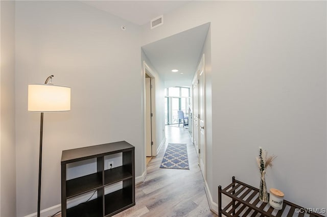 hallway with visible vents, recessed lighting, baseboards, and wood finished floors